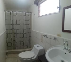 a bathroom with a toilet and a sink and a window at Hotel Ghiza in Tegucigalpa