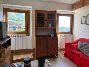 a living room with a red couch and two windows at Be Smiling Appartament in Passo del Tonale