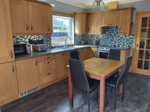 una cocina con armarios de madera y una mesa y sillas de madera. en Glencoe House Inverness en Inverness