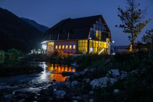 un gran edificio junto a un río por la noche en Hotel & Restaurant Ada en Gusinje