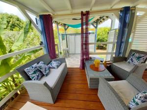 a porch with two chairs and a couch and a table at Villa de 2 chambres avec vue sur la mer piscine privee et jacuzzi a Bouillante in Bouillante