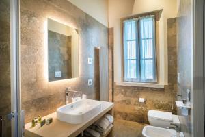 a bathroom with a sink and a toilet and a window at Villa Svetoni Wine Resort in Montepulciano