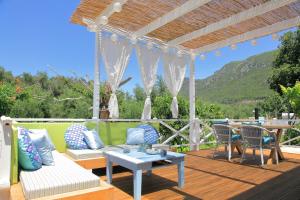 a patio with a couch and a table and chairs at BLUE SKY COTTAGE, Kanouli beach in Halikounas