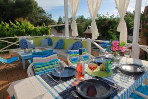 a table with plates and wine glasses on a patio at BLUE SKY COTTAGE, Kanouli beach in Halikounas