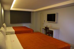 a hotel room with two beds and a desk and a tv at Hotel El Senador in Mexico City
