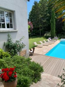 un patio trasero con piscina, sillas y flores en Maison d'Hôtes Joussaume Latour, en Château-Thierry