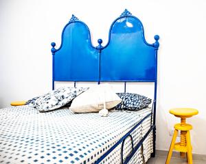 een slaapkamer met een blauw bed met kussens en een gele kruk bij Casa Nenè in Otranto