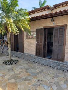 uma casa com uma palmeira na frente em Suítes Verano Ubatuba - Bairro Itaguá - com piscina em Ubatuba