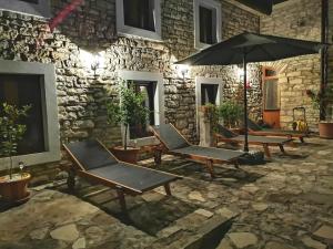 un groupe de chaises et un parasol devant un mur de pierre dans l'établissement Villa Rustica, à Buje