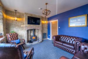 a living room with leather furniture and a stone fireplace at The Rockpool - private hot tub and sea views in Amble