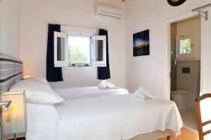 two beds in a white room with a window at BLUE SKY COTTAGE, Kanouli beach in Halikounas