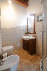 een badkamer met een wastafel, een toilet en een spiegel bij B&B Etruscan Garden in Sutri