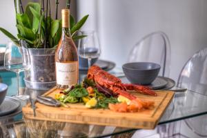 una mesa con un plato de comida y una botella de vino en The Rockpool - private hot tub and sea views en Amble
