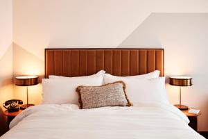 um quarto com uma grande cama branca e 2 candeeiros em The Hoxton, Holborn em Londres