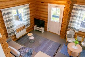 Cabaña de madera con sala de estar con sofá y TV. en Loma-Autio Aamurusko, en Puumala