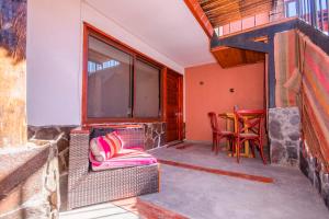 Un balcón con una silla de mimbre y una mesa. en Hotel Casa Algarrobo, en San Pedro de Atacama