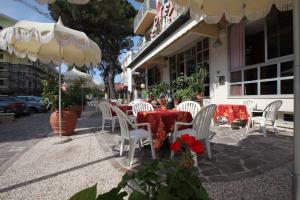 d'une terrasse avec des tables, des chaises et un parasol. dans l'établissement Hotel Baviera, à Sottomarina