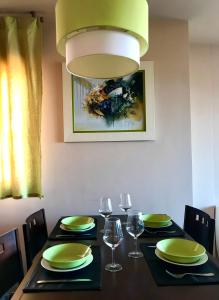 einen Esstisch mit grünen Tellern und Weingläsern in der Unterkunft VIVIENDA CORRUBEDO VISTA DUNAS in Corrubedo