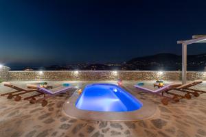 uma piscina à noite com dois salões e uma piscina em Peters Place - Paros Resort em Parasporos