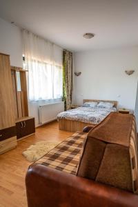 una camera con due letti e un divano in camera di Pensiunea VisAventura a Vişan