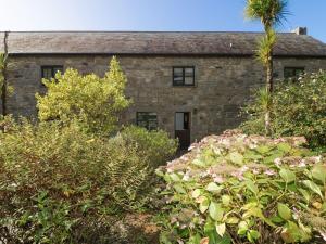 an old stone house with a palm tree and bushes at Valley Cottage in Penzance