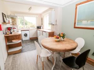 a kitchen with a wooden table and white chairs at 2 Thompsons Buildings in Choppington