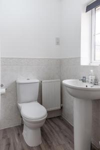 a white bathroom with a toilet and a sink at KVM Bluebird House for large groups by KVM Serviced Accommodation in Peterborough