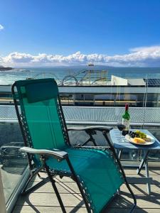 a green chair sitting next to a table with a bottle of wine at Portrush Penthouse in Portrush