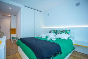 a bedroom with a large green bed with white pillows at Acqua House by Rent4All in Figueira da Foz