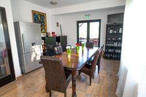 a dining room table with chairs and a refrigerator at Pensiunea VisAventura in Vişan
