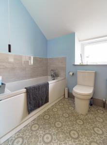 a bathroom with a toilet and a tub and a sink at Portrush Penthouse in Portrush