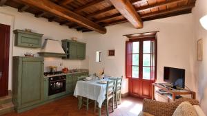 eine Küche mit grünen Schränken und einem Tisch mit Stühlen in der Unterkunft Raffaello in Gaiole in Chianti