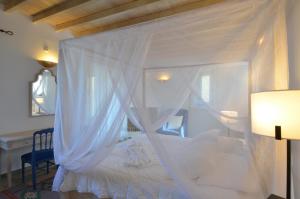 a bedroom with a white bed with a canopy at Aegea Blue Cycladic Resort in Zorgos 