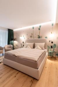 a bedroom with a large white bed with flowers on the wall at Genusshotel Sackmann in Baiersbronn