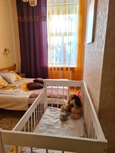 a teddy bear sitting in a crib in a bedroom at Libau Baden apartamenti in Liepāja