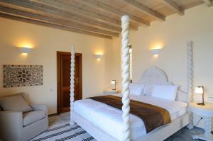 a bedroom with a white bed and a chair at Aegea Blue Cycladic Resort in Zorgos 