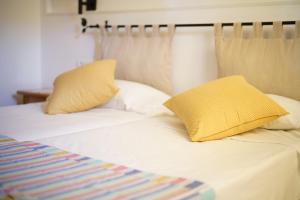 un letto con due cuscini gialli sopra di Hostal Yebisah a Santa Eularia des Riu