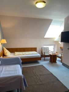 a bedroom with two beds and a couch and a window at Hotel Weller in Riedstadt