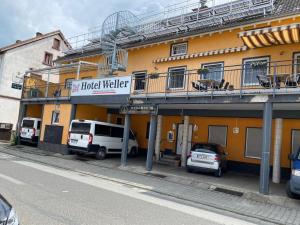 a building with a balcony and cars parked in front of it at Hotel Weller in Riedstadt