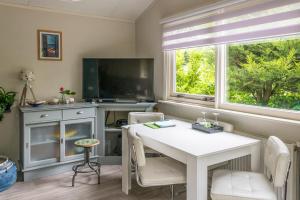 comedor con mesa blanca y TV en Klein Heemshof - Noord Holland aan uw voeten, en Warmenhuizen