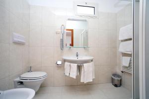 a bathroom with a sink and a toilet and a mirror at Bikini Hotel in Vieste