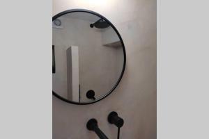 a round mirror hanging on a wall in a bathroom at Το Παράσπιτο in Skiros