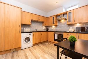 a kitchen with wooden cabinets and a washer and dryer at Oakstays Central Gem in Newcastle upon Tyne