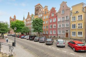 a row of cars parked on a street with buildings at Dom & House - Old Town Swietego Ducha in Gdańsk