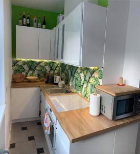 kuchnia z białymi szafkami i mikrofalówką w obiekcie Apartament nad Kryniczanką w mieście Krynica Zdrój