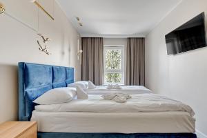 a bedroom with a large bed with a blue headboard at Wave Apartments - Mezzo in Gdańsk