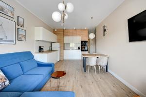 a living room with a blue couch and a kitchen at Wave Apartments - Mezzo in Gdańsk