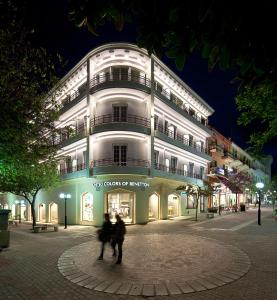 un edificio con gente caminando delante de él por la noche en Hotel Hermes en Rodas