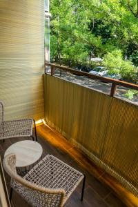 un balcone con 2 sedie, un tavolo e una finestra di Secret Garden Apartman a Miskolc