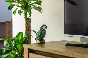une statue d'oiseau assise sur une table à côté d'une télévision dans l'établissement Secret Garden Apartman, à Miskolc